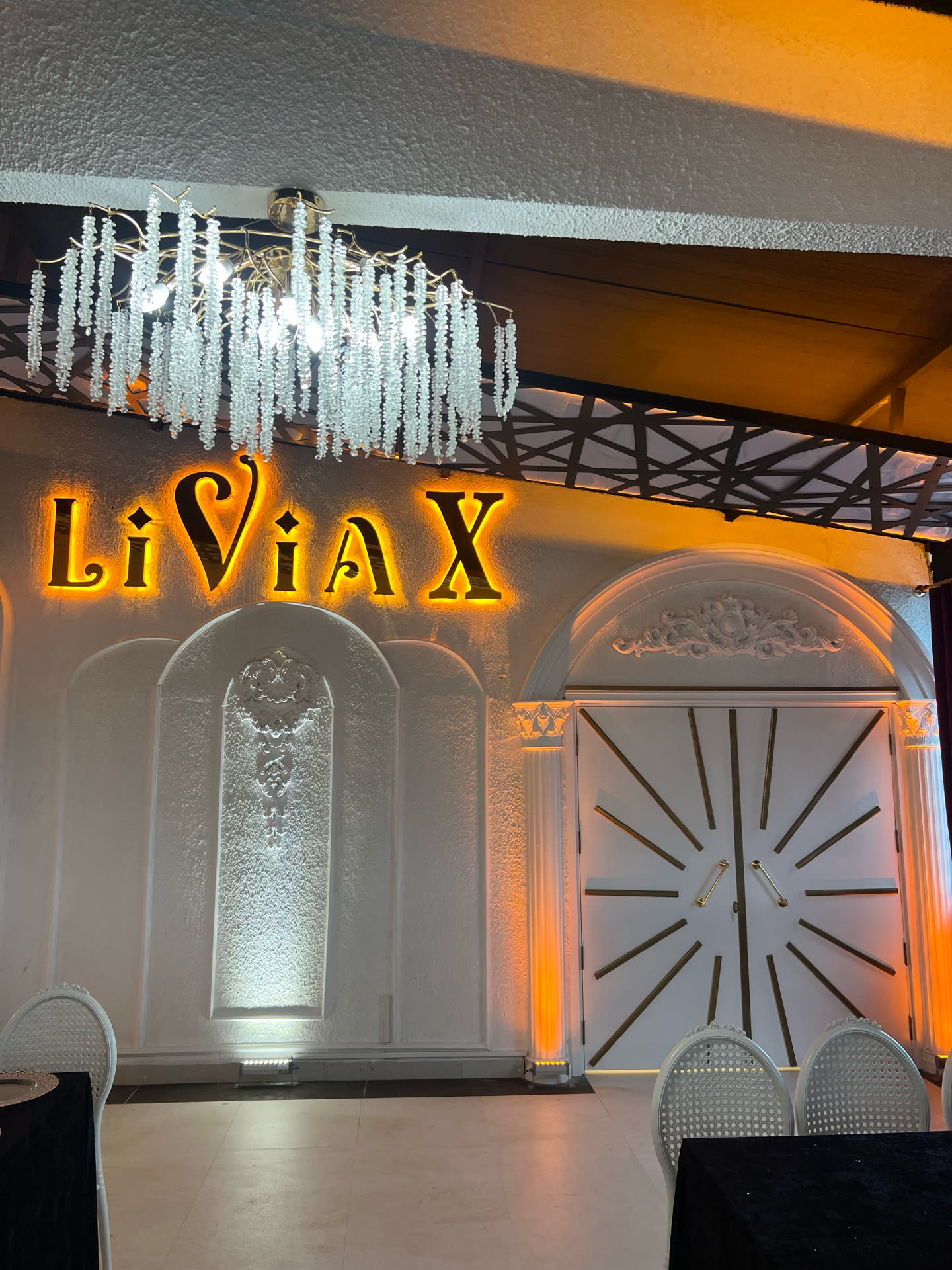LiviaX tabelası, kristal avize ve güneş desenli beyaz kapılar